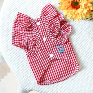 Détail de robe vichy rouge pour chien avec volants et boutons sur fond texturé doux