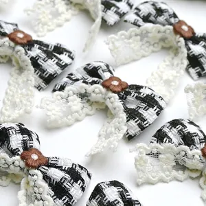 Detailed view of handmade black and white plaid bow clips with white lace and floral buttons