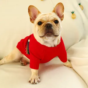 Close-up of a French Bulldog wearing a red Christmas reindeer knit sweater in cozy lighting