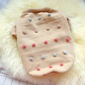 Detailed close-up of knitted pet sweater with colorful 3D pom-poms and ribbed edges