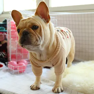 Detail view of beige knit pet sweater with colorful pom-poms on a French Bulldog