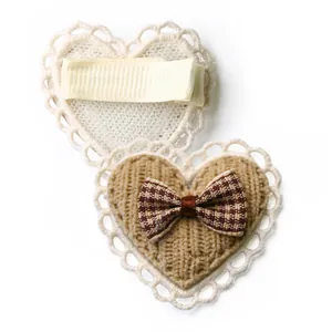 Detail of heart-shaped lace hair clip with brown plaid bow and metal duckbill clip