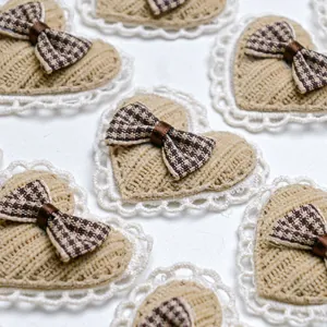 Detail of a beige knit heart hair clip with white lace trim and brown plaid bow