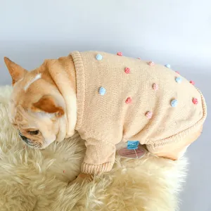 Detail of beige knit pet sweater featuring colorful pom-poms and ribbed cuffs for Frenchies