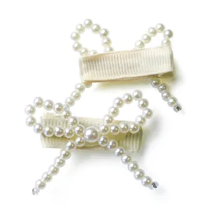 Close-up of elegant handmade pearl bow hair clips for dogs with ribbon-wrapped metal duckbill clips