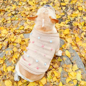 Detail of a khaki knitted pet sweater with colorful pom-poms on a French Bulldog