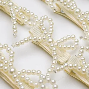 Detail of elegant cream faux pearl bow hair clip with fabric-wrapped clip base
