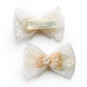 Detail view of lace bow pet hair clips with gold thread pattern and pearl flower centers