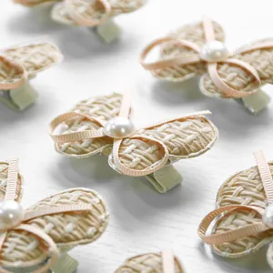 Detailed view of handmade bow pet hair clips with pearls and textured fabric on white background
