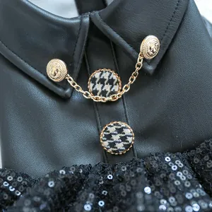 Detail van huisdierjasje met gouden leeuwenkopknopen, kettingen en zwarte lovertjes
