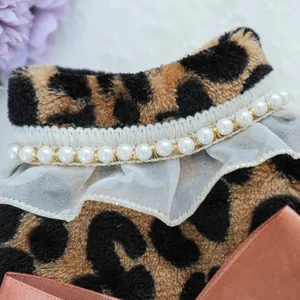 Detailed view of leopard print pet dress featuring faux pearls and mesh ruffles