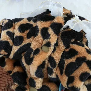 Close-up of leopard print plush pet clothing with white lace, pearls, and metal snaps