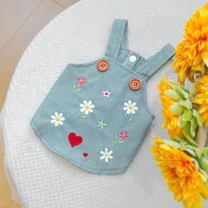 Dettaglio del gilet per animali con fiori ricamati e cuori rossi su velluto verde