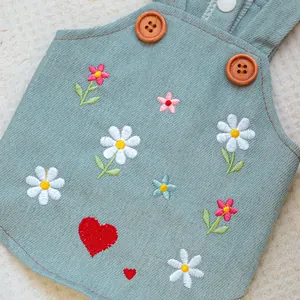 Close-up of denim pet dress with floral embroidery, daisy heart patterns and wood buttons