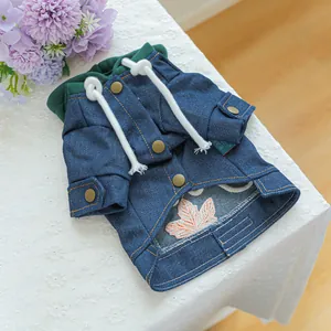 Detail van honden denim hoodie met marineblauwe stof en oranje esdoornblad borduursel