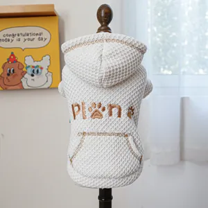 Detail of cream waffle fabric pet hoodie with brown pocket and embroidered paw print