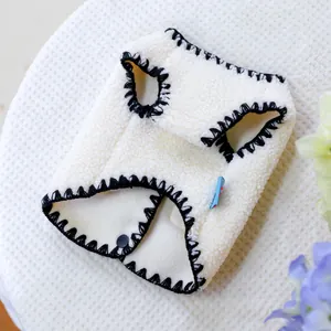 Detail der cremefarbenen Fleece-Haustierweste mit schwarzem Saum und Druckknopf