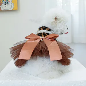 Detail of elegant pet dress with leopard print collar and large brown satin bow on white dog
