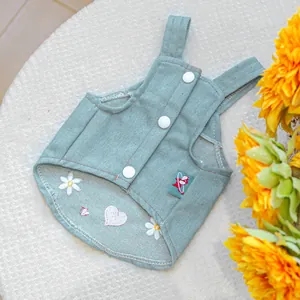 Dettaglio dell'abito per animali in denim blu chiaro con ricami a margherita e bottoni bianchi