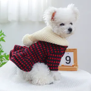 Dettaglio vestito per cani a quadri rossi e neri con cappuccio crema e pompon
