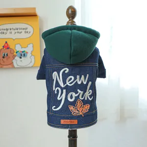 Detailweergave van denim huisdierenvest met New York borduursel en groene capuchon op pop