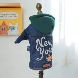 Detail van spijkerjasje voor huisdieren met New York borduursel en groene capuchon op model