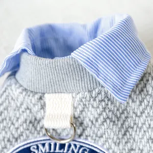 Detail of grey knitted pet vest with D-ring, shirt collar, and smiling embroidery