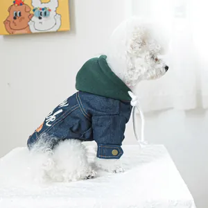 Detail van spijkerjasje voor honden met groene capuchon en wit borduursel op rug