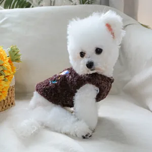 Primo piano di un cane bianco con un caldo gilet di pile marrone scuro e motivi
