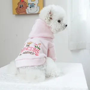 Détail d'un sweat à capuche rose pour chien avec broderie princesse sur un chiot blanc