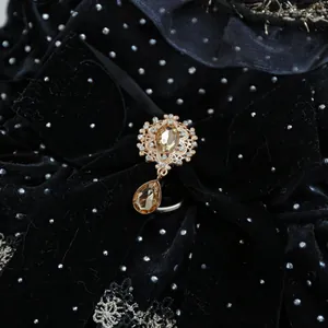Détail d'une broche dorée vintage avec pierres champagne sur robe velours noire