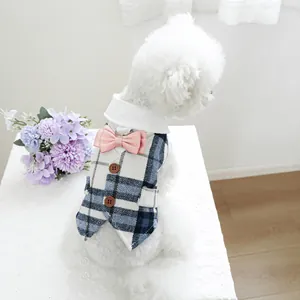 Detail of blue plaid pet vest featuring a pink satin bow and wooden buttons for dogs