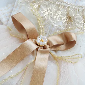 Dettaglio di elegante vestito per animali con fiocco di raso, fiore di perle e pizzo dorato