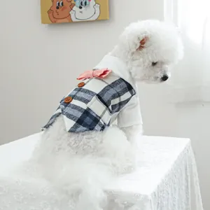 Detail of blue plaid pet tuxedo with pink bow tie and brown buttons on white dog