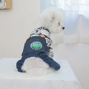 Petit chien blanc portant une chemise imprimée et une salopette en jean sur dentelle