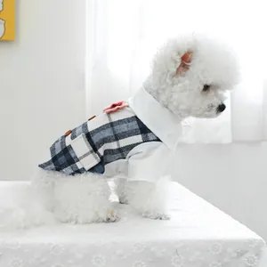 Detailed close-up of blue plaid dog tuxedo with vintage buttons and pink flower accessory