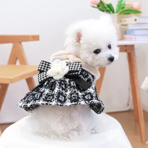 Dettaglio vestito cane con motivo pied-de-poule, grande fiocco nero e fiore di camelia