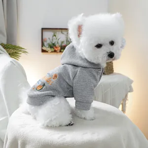 Detail of grey waffle knit dog hoodie with orange fruit embroidery and hood on white dog