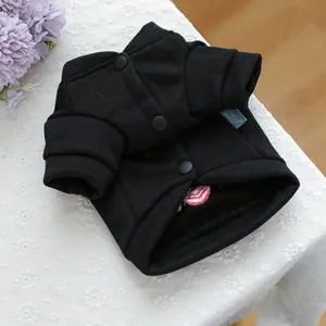 Detalle de chaqueta negra para mascotas de algodón con botones mate y etiqueta azul tejida