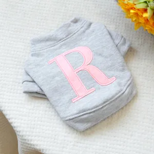Detalle de jersey gris para mascotas con letra R rosa bordada en tejido de algodón
