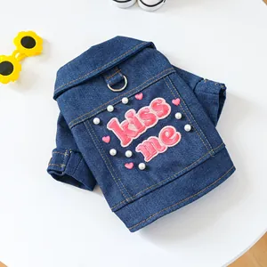 Detail der blauen Denim-Hundeweste mit rosa Kiss Me-Stickerei und weißen Perlen