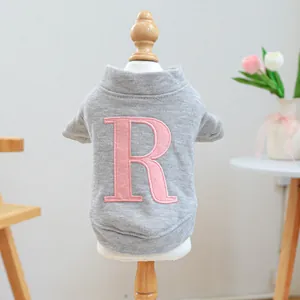 Detalle de suéter gris para mascotas con bordado R rosa en maniquí de madera