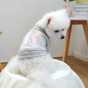 Detalle de sudadera gris para perro con bordado rosa sobre un bichón frisé blanco