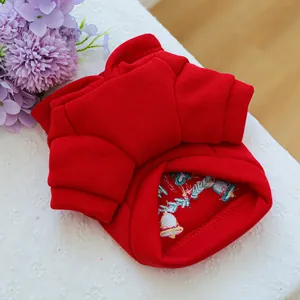 Close-up of red pet sweater with festive gold bell and holly embroidery detail
