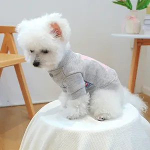 Detalle de sudadera gris para perro con gráfico rosa y etiqueta azul en perro blanco