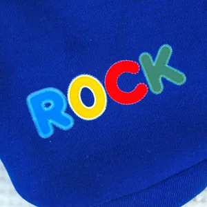 Gros plan détaillé du sweat à capuche bleu pour chien avec broderie ROCK colorée