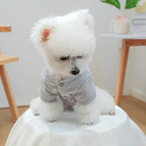 Primer plano de un perro blanco pequeño con un cárdigan gris suave para mascotas con botones