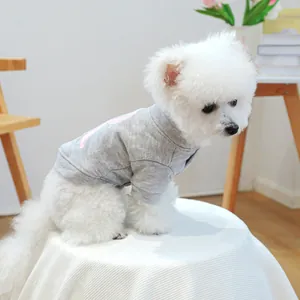 Sudadera gris oscuro para mascotas con estampado rosa usada por un perro blanco pequeño en casa