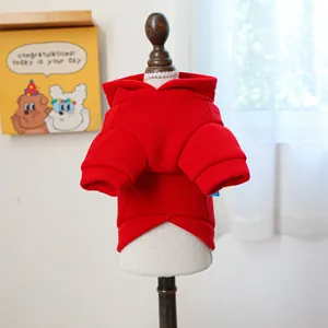 Close-up of a red pet hoodie with ribbed cuffs on a wooden mannequin in a cozy room