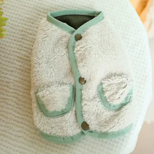Macro detail of plush white fleece pet vest with green trim and brown buttons